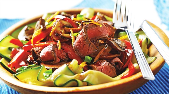 Slices of beef, zucchini ribbons and red peppers in a bowl