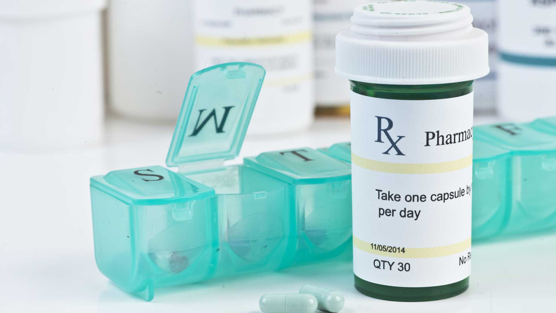 Daily medication dispenser with green prescription bottle and pills
