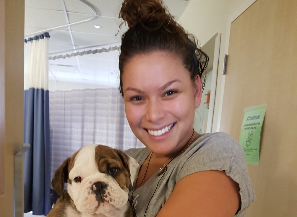 Samantha smiling while carrying a dog